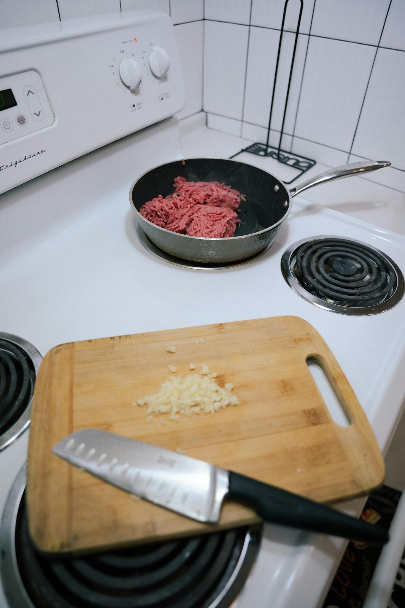 Preparing ground beef and minced garlic on a kitchen stove for a delicious meal.